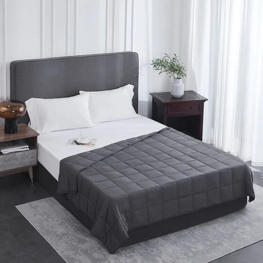 Bed with gray comforter and pillows in a bedroom setting